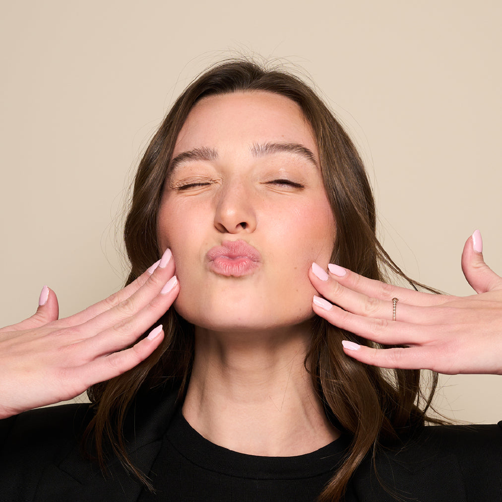 woman puckering her lips and touching her cheeks