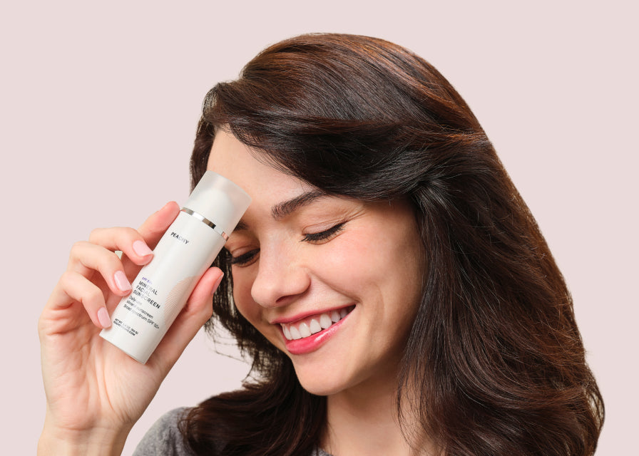 woman touching Mineral Facial Sunscreen container to forehead