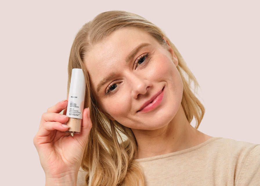 woman holding Mineral Powder Sunscreen to side of head