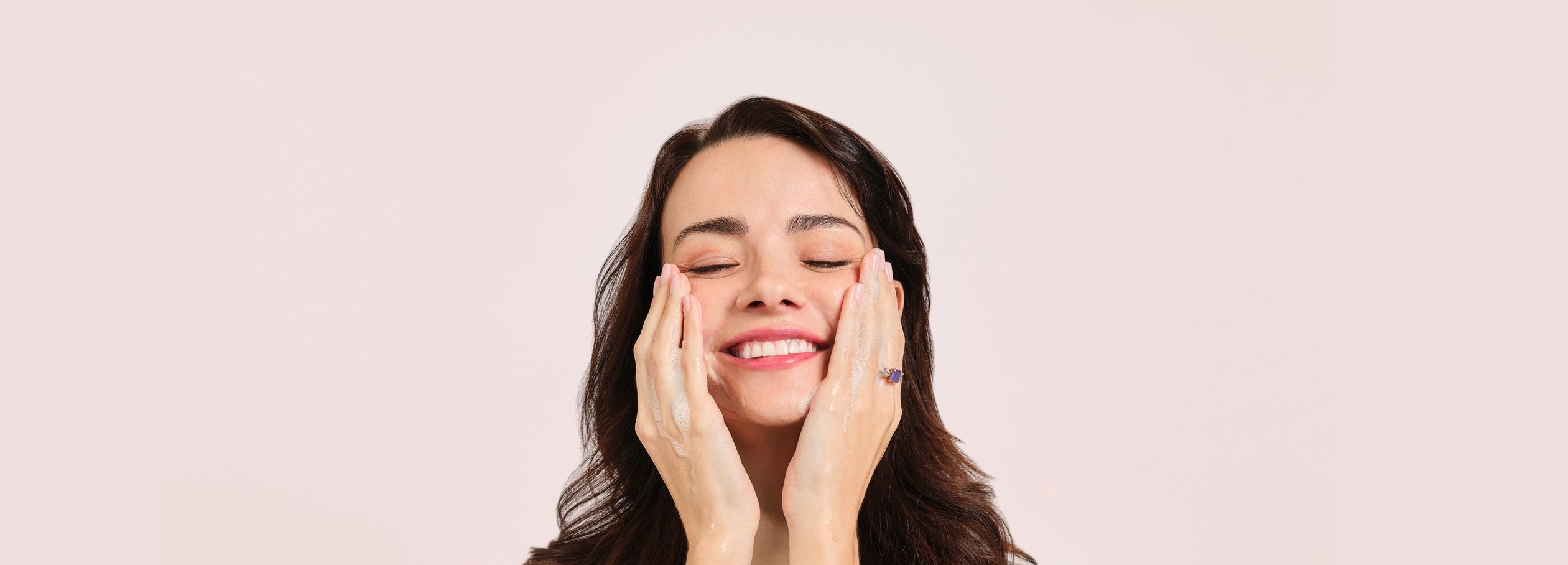 woman washing face with hands on cheeks