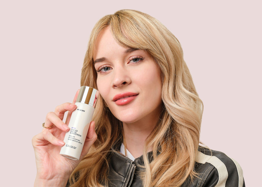 woman touching Tinted Facial Sunscreen container to cheek