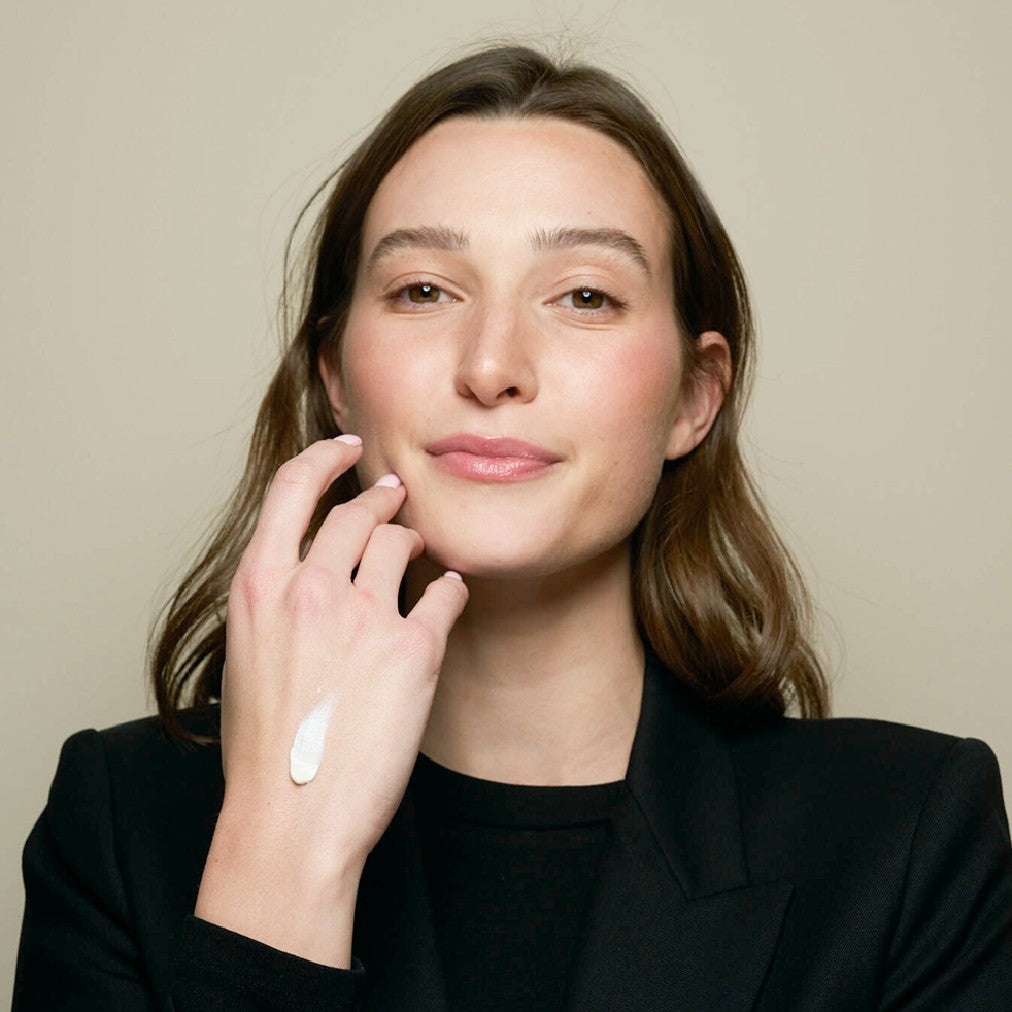 Woman with lotion on back of hand with a neutral background