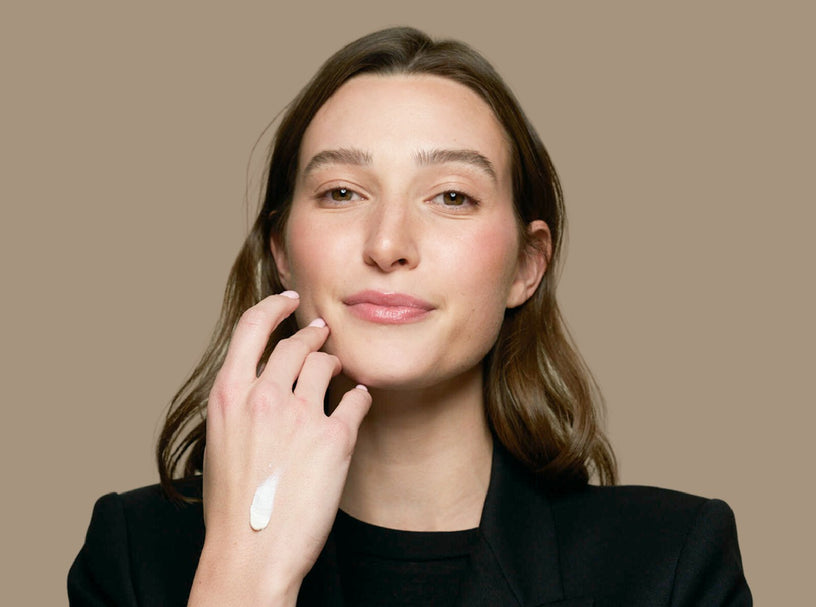 Woman with lotion on back of hand with a neutral background