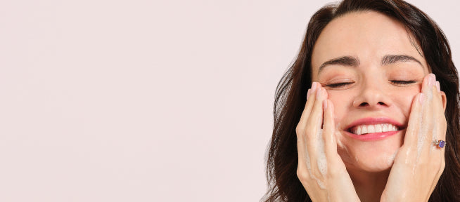 woman washing face with hands on cheeks