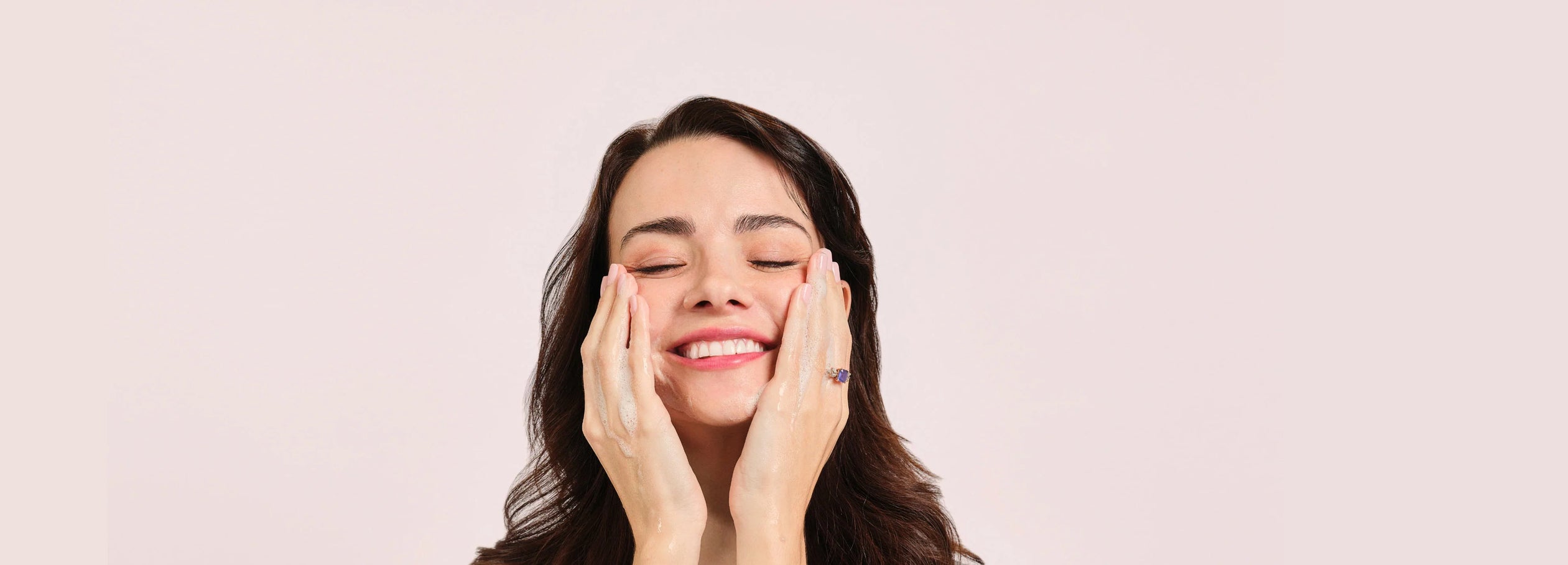 woman washing face with hands on cheeks