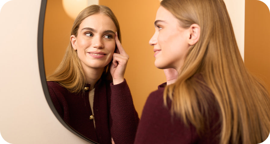 woman looking at face in mirror