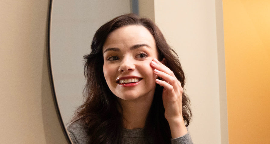 Woman looking in mirror and touching cheekbones